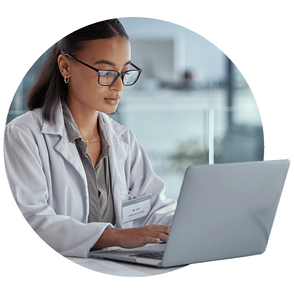 Female doctor in white coat and glasses working on a laptop computer